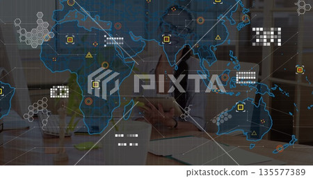 Holding tablet, woman in button-down shirt exploring network overlay at office desk, with monitor 135577389