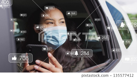 Holding smartphone masked passenger checking notification icons inside car near open window frame 135577412