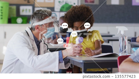 Measuring school nurse wearing mask taking student temperature inside classroom, with thermometer 135577423