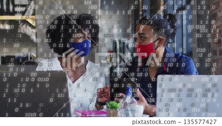 Discussing project two masked colleagues using laptops in cafe, with succulent and binary overlay Discussing project two masked colleagues using laptops in cafe, with succulent and binary overlay 135577427