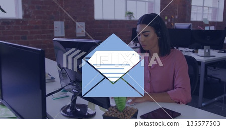 Support agent wearing pink blouse typing in office, with monitor, headset, papers, copy space Support agent wearing pink blouse typing in office, with monitor, headset, papers, copy space 135577503