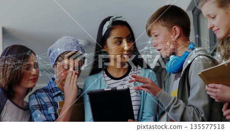 Collaborating five students gathering around tablet in school corridor, with face recognition 135577518