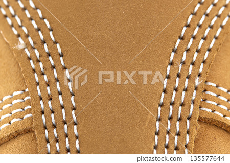Close-up of tan suede material with detailed white stitching on a shoe or boot Close-up of tan suede material with detailed white stitching on a shoe or boot 135577644