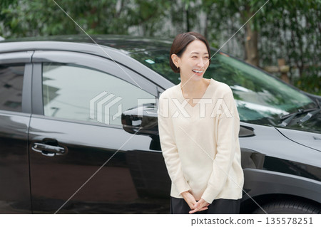 A woman in her 30s standing in front of a car 135578251