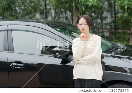 一名三十多歲的女子站在一輛車前。 135578255