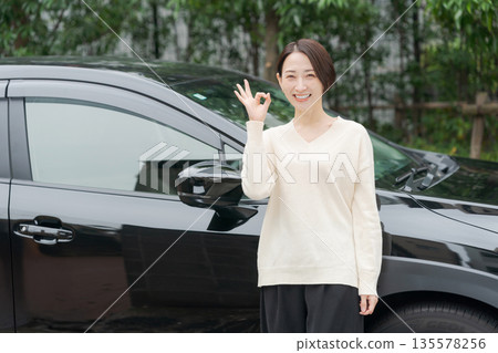 一名三十多歲的女子站在一輛車前。 135578256
