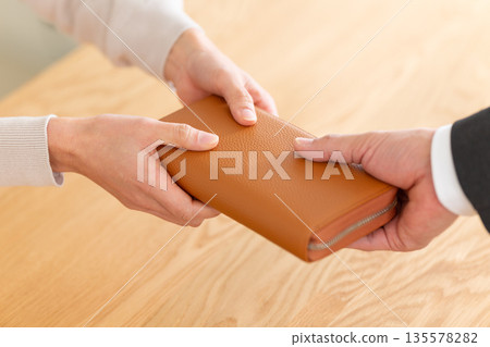 A middle-aged couple handing over their wallets A middle-aged couple handing over their wallets 135578282