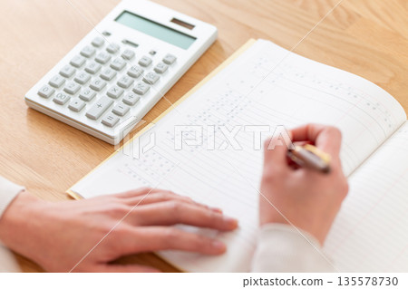 A middle-aged woman keeping a household account book A middle-aged woman keeping a household account book 135578730