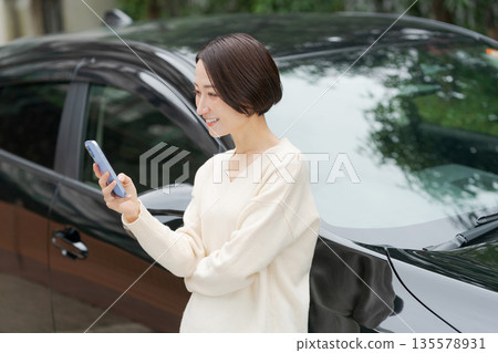 一名女子在車前操作智慧型手機 135578931