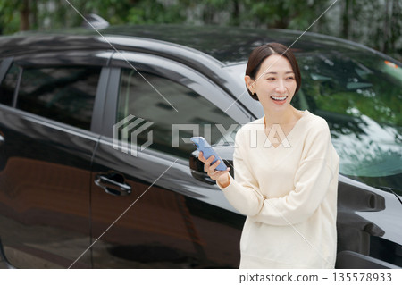 一名女子在車前操作智慧型手機 135578933