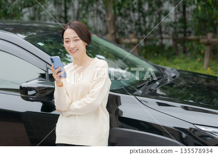 一名女子在車前操作智慧型手機 135578934