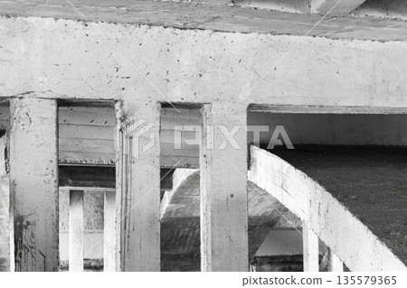 Monochrome scene showing rugged concrete pillars and curved ramp Monochrome scene showing rugged concrete pillars and curved ramp 135579365