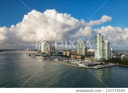 Marina Bay filled with vessels and yacht in Miami. Summer vacation scene with yachts by the oceanfront. Skyline with yachts in Miami. Florida coastline from above with boats. Boat trip in the Miami. Marina Bay filled with vessels and yacht in Miami. Summer vacation scene with yachts by the oceanfront. Skyline with yachts in Miami. Florida coastline from above with boats. Boat trip in the Miami. 135579584