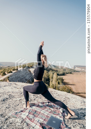 Yoga on the Cliffside: Woman Practicing Warrior Pose with a View Yoga on the Cliffside: Woman Practicing Warrior Pose with a View 135579904