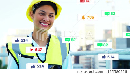 Smiling engineer wearing hard hat, vest, holding tablet on rooftop terrace, with notification icons Smiling engineer wearing hard hat, vest, holding tablet on rooftop terrace, with notification icons 135580326