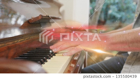 Playing piano, man pressing ivory keys in music room by window with sparkle overlay, copy space Playing piano, man pressing ivory keys in music room by window with sparkle overlay, copy space 135580439