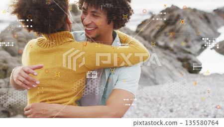 Couple hugging on pebble beach wearing lightblue Tshirt and mustardyellow sweater, with AR overlays 135580764