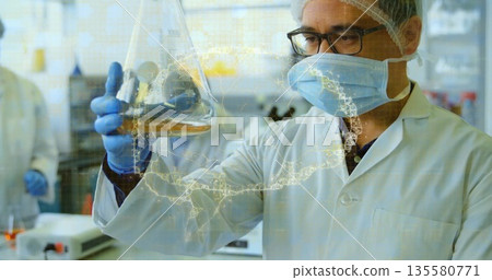Inspecting scientist wearing protective gear holding yellow solution flask in lab, with DNA overlay 135580771