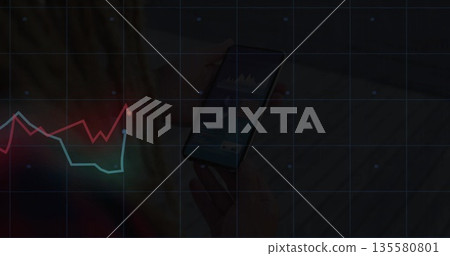Displaying hands holding smartphone showing data charts at desk featuring grid overlay, line graphs 135580801
