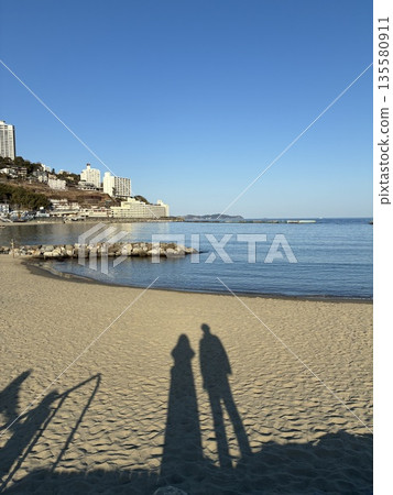 兩個人的影子投射在沙灘上。 兩個人的影子投射在沙灘上。 135580911