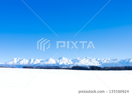 Winter blue sky and the majestic scenery of the Tokachi mountain range seen from the hills of Biei, Hokkaido 135580924