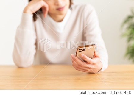 一位中年婦女擔心她房間裡的智慧型手機。 135581468