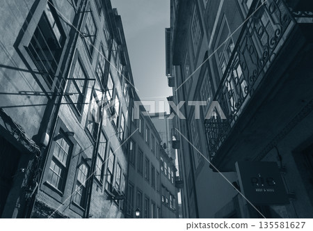 Dark narrow alley between old European buildings in cold monochrome tone. Mysterious atmosphere with Dark narrow alley between old European buildings in cold monochrome tone. Mysterious atmosphere with 135581627