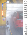 Close up view of a red car inside an automatic car wash with water spray and foam. 135582120