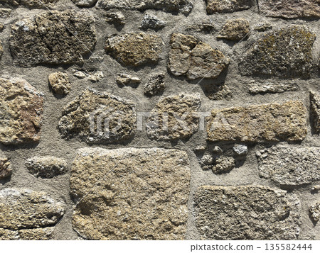 Close-up texture of an old stone wall made from irregularly shaped rocks and mortar. The surface Close-up texture of an old stone wall made from irregularly shaped rocks and mortar. The surface 135582444