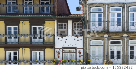 Colorful traditional houses in the old town of Guimaraes, Portugal. The charming facades feature Colorful traditional houses in the old town of Guimaraes, Portugal. The charming facades feature 135582452