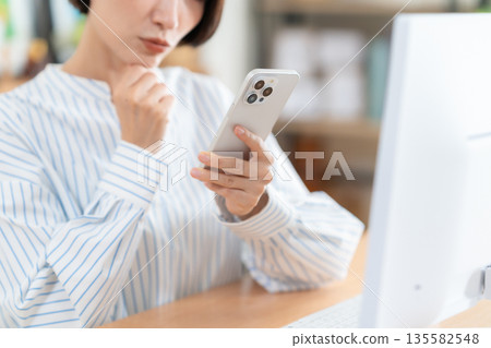Middle-aged woman teleworking in the living room Middle-aged woman teleworking in the living room 135582548