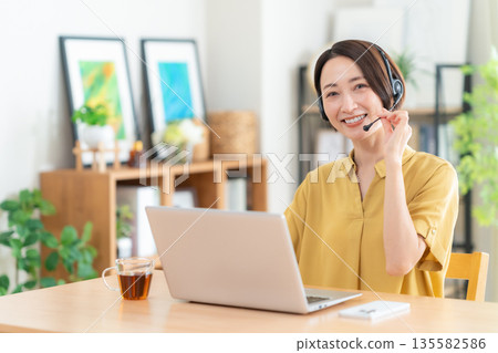 Middle-aged woman looking at a computer in the living room 135582586
