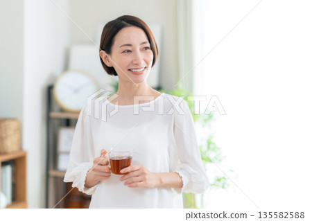 Middle-aged woman drinking tea in the living room 135582588