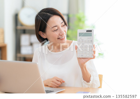 A middle-aged woman keeping a household account book in the living room 135582597