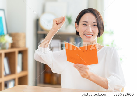 一位中年婦女在客廳看著她的退休金簿。 135582609