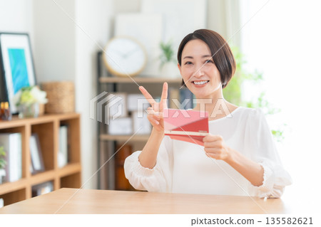 A middle-aged woman looking at her savings passbook in the living room A middle-aged woman looking at her savings passbook in the living room 135582621