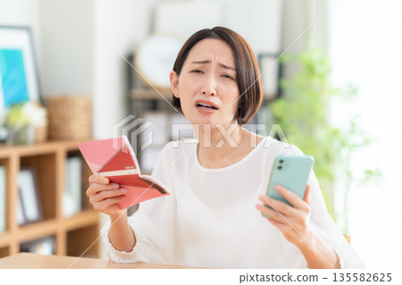 一位中年婦女在客廳查看她的儲蓄存摺。 135582625