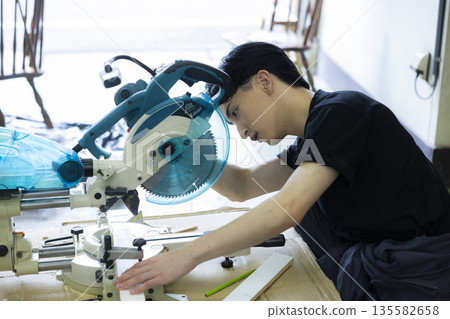 Man using a sliding circular saw Man using a sliding circular saw 135582658