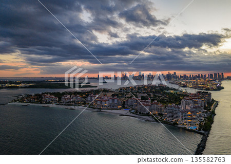 Aerial night view of Miami coastline. Twilight skyline above the Miami oceanfront. Miami Beach waterfront with dramatic sky. Aerial night view of Miami coastline. Twilight skyline above the Miami oceanfront. Miami Beach waterfront with dramatic sky. 135582763