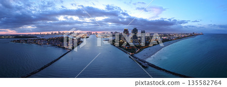 Aerial view of night South Beach coastline. Miami skyline with tropical blue waters panorama. Panorama over the Miami skyscrapers at dusk. 135582764