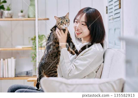 A smiling Japanese woman holding a cat 135582913