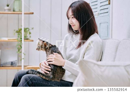 一位微笑的日本女子抱著一隻貓 一位微笑的日本女子抱著一隻貓 135582914