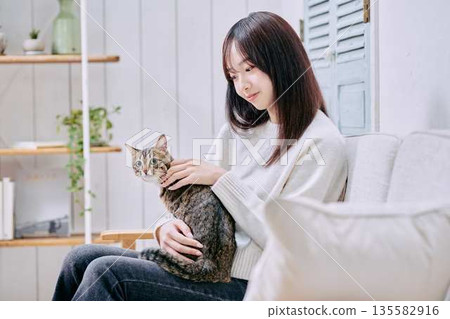 一位微笑的日本女子抱著一隻貓 一位微笑的日本女子抱著一隻貓 135582916