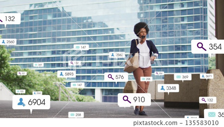 Walking businesswoman using smartphone and carrying tote bag in office plaza with floating overlays Walking businesswoman using smartphone and carrying tote bag in office plaza with floating overlays 135583010