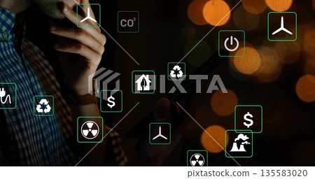 Standing man in plaid shirt holding tablet touching chin at office floating eco icons, copy space Standing man in plaid shirt holding tablet touching chin at office floating eco icons, copy space 135583020