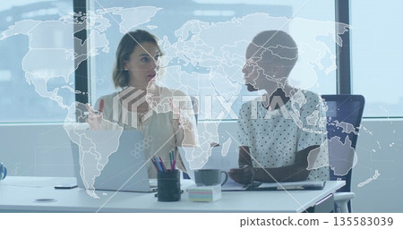 Discussing data, two colleagues using silver laptop and gesturing at office desk, with smartphone Discussing data, two colleagues using silver laptop and gesturing at office desk, with smartphone 135583039
