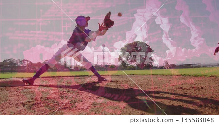 Lunging ballplayer in cap scooping ground ball on baseball field, with glove and white ball 135583048
