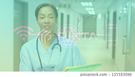 Standing nurse in scrubs, holding folder with stethoscope in hospital corridor, with digital icons Standing nurse in scrubs, holding folder with stethoscope in hospital corridor, with digital icons 135583086