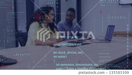 Developers wearing business attire reviewing programming code at conference table, with laptops Developers wearing business attire reviewing programming code at conference table, with laptops 135583109