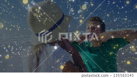 Adjusting straw hat, white-tee girl and green-tee boy pulling face at shoreline amid golden flecks Adjusting straw hat, white-tee girl and green-tee boy pulling face at shoreline amid golden flecks 135583145